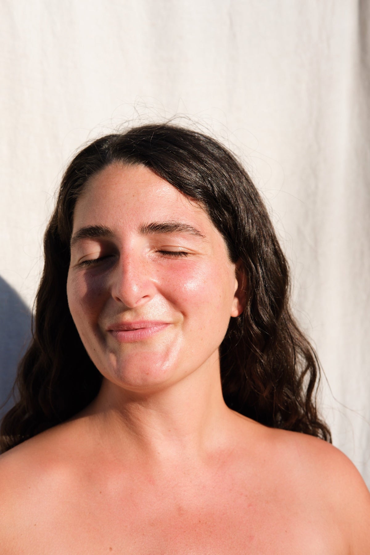Woman with closed eyes against a plain background