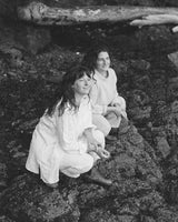 rhea founders in white outfits sitting on rocks in the pacific northwest